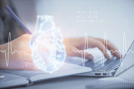 Double exposure of woman hands typing on computer and heart hologram drawing. Education concept.の写真素材