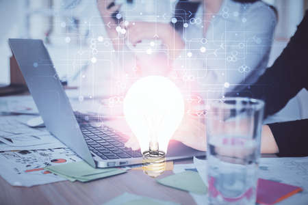 Double exposure of woman hands typing on computer and light bulb drawing. Idea concept.の写真素材