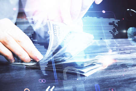 Double exposure of world map drawing hologram and us dollars bills and man hands.の写真素材