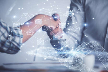 Double exposure of envelop flying in air drawing hologram and handshake of two men. E-mail concept.