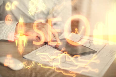 Multi exposure of man's hands holding and using a digital device and seo drawing. search optimization concept.の写真素材