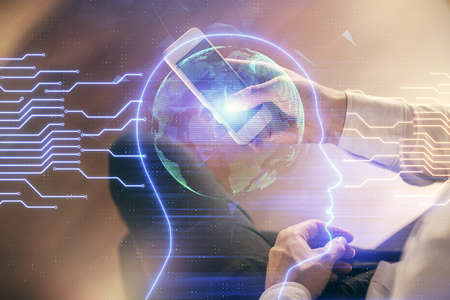 Double exposure of man's hand holding and using a digital device and brain hologram drawing. Data...