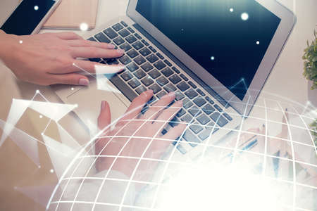 Double exposure of woman hands working on computer and world map hologram drawing. International...