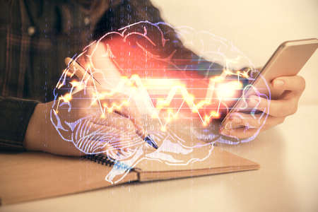 Double exposure of brain sketch hologram and woman holding and using a mobile device.