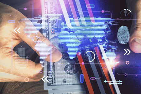 Double exposure of world map drawing hologram and us dollars bills and man hands.