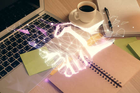 Double exposure of handshake drawing and desktop with coffee and items on table background. Concept of partnershipの写真素材