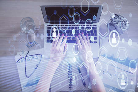 Double exposure of woman hands working on computer and social network theme hologram drawing. Top...