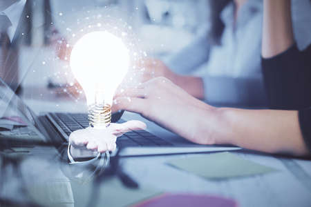 Double exposure of woman hands typing on computer and light bulb drawing. Idea concept.