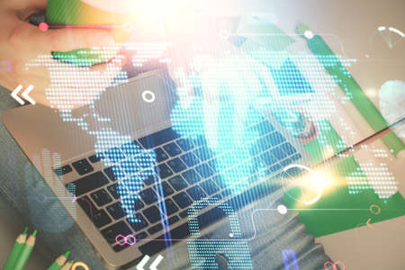 Double exposure of woman hands working on computer and world map hologram drawing. International...