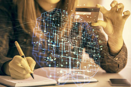 Double exposure of woman on-line shopping holding a credit card and brain hologram drawing. Data...