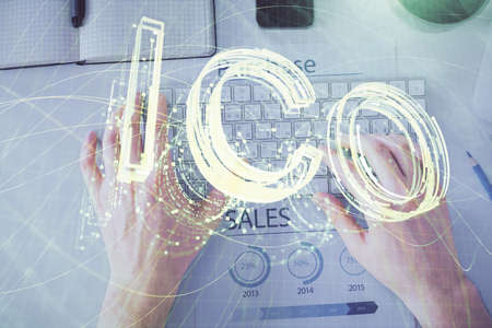 Double exposure of man's hands typing over computer keyboard and crypto currency theme hologram...