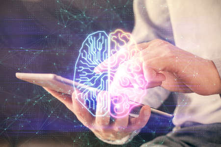 Double exposure of man's hand holding and using a digital device and brain hologram drawing. Data...