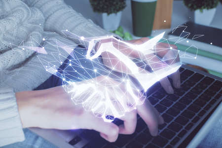 Double exposure of woman hands typing on computer and handshake drawing. Partnership concept.