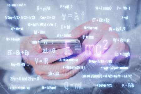 Double exposure of man's hands holding and using a phone and formulas drawing. Education concept.の写真素材