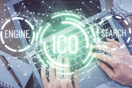 Double exposure of man's hands typing over computer keyboard and crypto currency theme hologram...