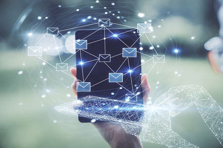 Double exposure of envelop icon hologram and woman holding and using a mobile device. E-mail concept.の写真素材