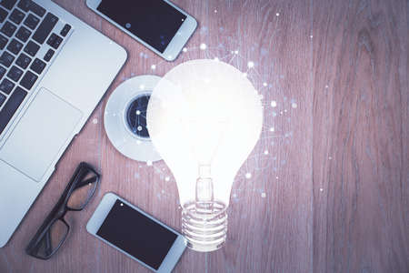 Double exposure of bulb drawing over table with phone. Top view. Concept of idea.の写真素材