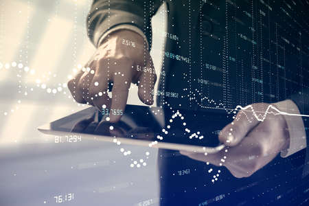 Double exposure of man's hand holding and using a digital device and data theme hologram drawing. Technology concept.の写真素材