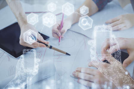 Double exposure of tech theme hologram and man and woman working together holding and using a mobile device.の写真素材