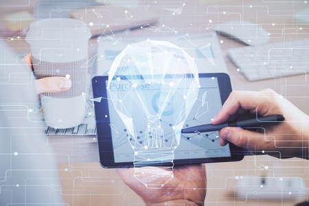 Double exposure of man's hands holding and using a digital device and bulb hologram drawing. Idea concept.の写真素材
