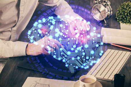 Double exposure of man's hand holding and using a digital device and brain hologram drawing. Data...