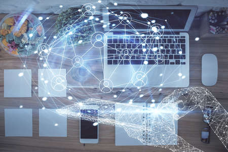 Social network hologram drawings over computer on the desktop background. Top view. Double exposure.