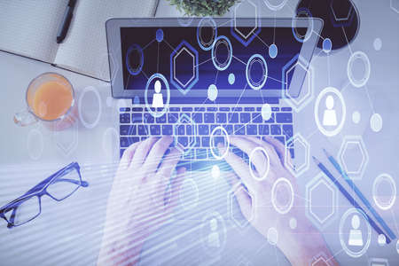 Double exposure of man's hands typing over computer keyboard and social network theme hologram...