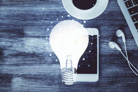 Double exposure of bulb drawing over table with phone. Top view. Concept of idea.の写真素材