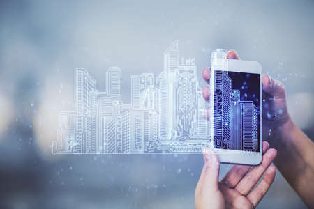 Double exposure of buildings hologram and woman holding and using a mobile device. Smart city...
