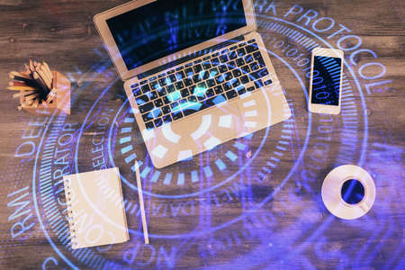 Double exposure of data drawing hologram over topview of study desk background with computer....