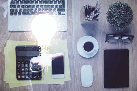 Double exposure of bulb drawing over table with phone. Top view. Concept of idea.の写真素材