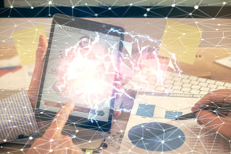 Double exposure of man's hand holding and using a digital device and brain hologram drawing. Data...