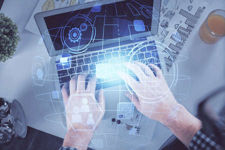 Double exposure of man's hands typing over computer keyboard and social network theme hologram...