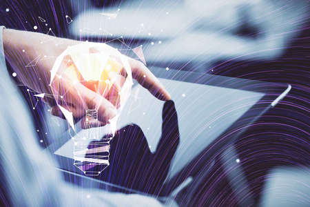 Double exposure of man's hands holding and using a digital device and bulb hologram drawing. Idea concept.の写真素材