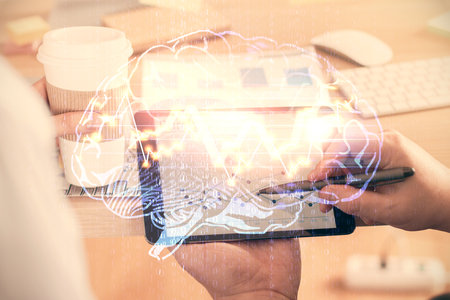 Double exposure of man's hand holding and using a digital device and brain hologram drawing. Data...