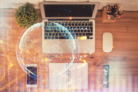 Double exposure of map hologram drawing over study table background with computer. Concept of international network. Top view.の写真素材