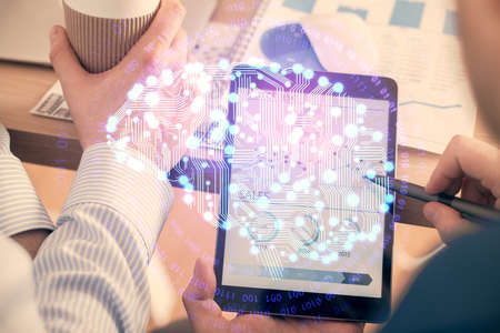 Double exposure of man's hand holding and using a digital device and brain hologram drawing. Data...