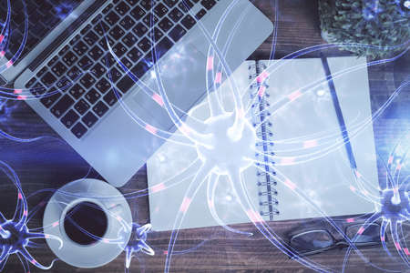 Neuron hologram drawings over computer on the desktop background. Top view. Multi exposure. Concept of education.の写真素材