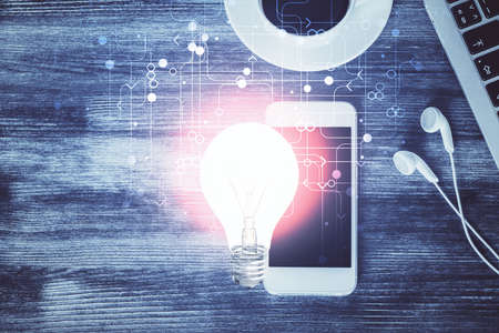 Double exposure of bulb drawing over table with phone. Top view. Concept of idea.の写真素材