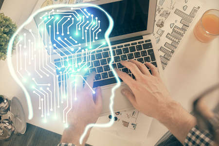 Double exposure of man's hands typing over computer keyboard and brain hologram drawing. Top view....