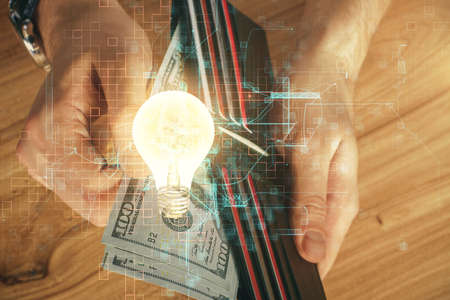Multi exposure of bulb drawing hologram and USA dollars bills and man hands. Business Idea concept.の写真素材