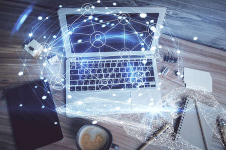 Social network hologram drawings over computer on the desktop background. Top view. Multi exposure....