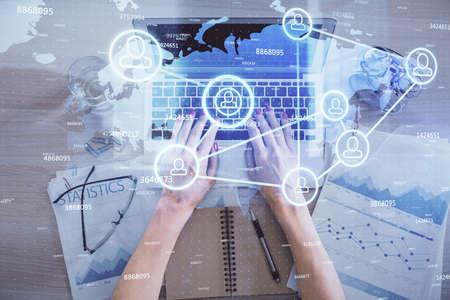 Double exposure of woman hands working on computer and social network theme hologram drawing. Top...