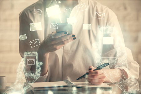 Double exposure of envelop icon hologram and woman holding and using a mobile device. E-mail concept.の写真素材