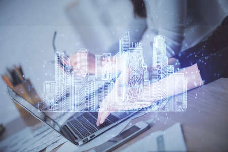 Double exposure of woman hands typing on computer and buildings drawing. Smart-city concept.