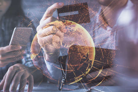 Double exposure of man and woman on-line shopping holding a credit card and social network theme hologram drawing. People connecting and E-commerce pay on-line concept.の写真素材