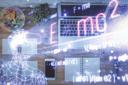 Physics and math theme hologram with formula drawings over computer on the desktop background. Top...