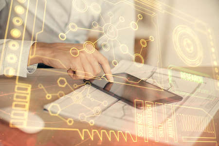 Double exposure of man's hand holding and using a digital device and data theme hologram drawing....