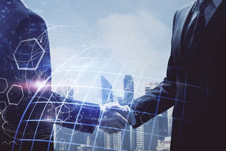 Double exposure of world map hologram and handshake of two men. International partnership concept.