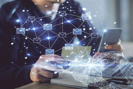 Double exposure of man's hands holding and using a digital device and envelop hologram drawing. E-mail concept.の写真素材